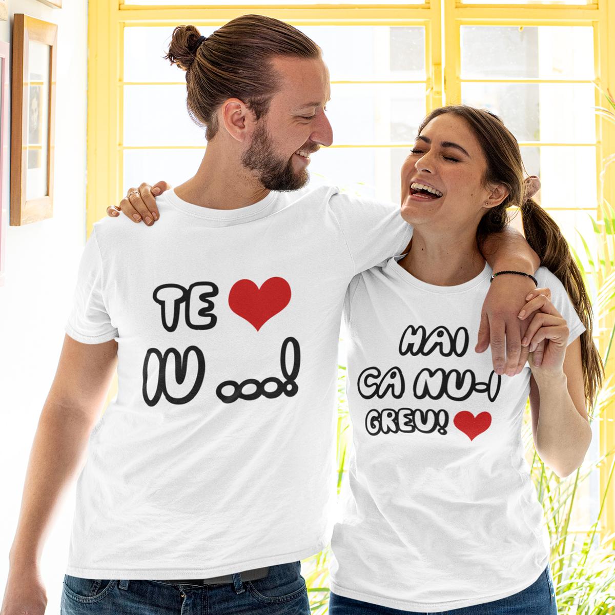 Set de două tricouri albe pentru cuplu, cu mesajul haios 'Te iu...!' și 'Hai că nu-i greu!', purtate de un bărbat și o femeie care zâmbesc.